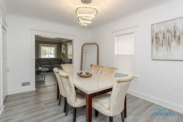 1129 Mason St, Toledo, OH 43605 - dining space with baseboards, a chandelier, light wood-style floors, and arched walkways