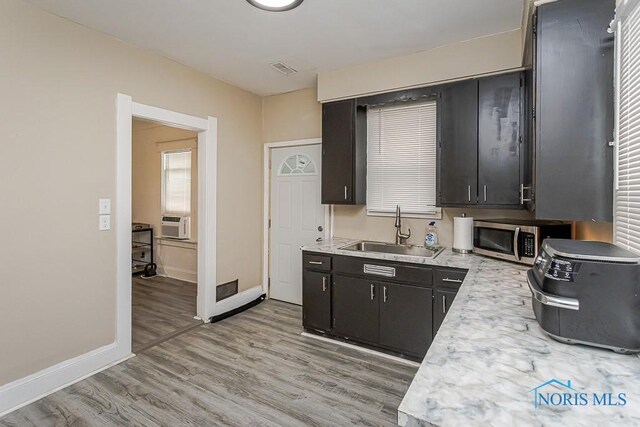 1129 Mason St, Toledo, OH 43605 - kitchen with a sink, stainless steel microwave, light countertops, baseboards, and light wood-style floors