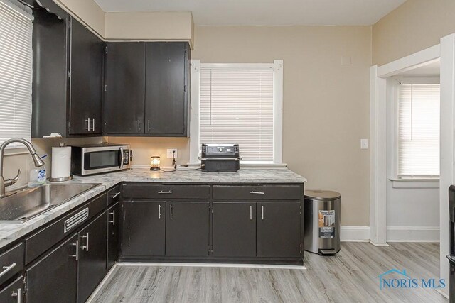 1129 Mason St, Toledo, OH 43605 - kitchen with stainless steel microwave, a sink, light wood-type flooring, and baseboards