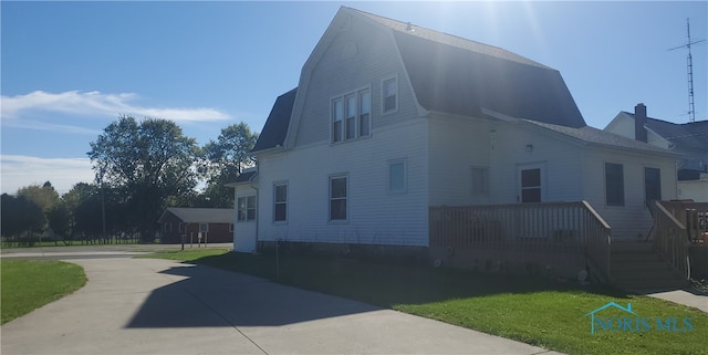 406 S State St, Pioneer, OH 43554 - view of property exterior with a gambrel roof, a wooden deck, a yard, and concrete driveway