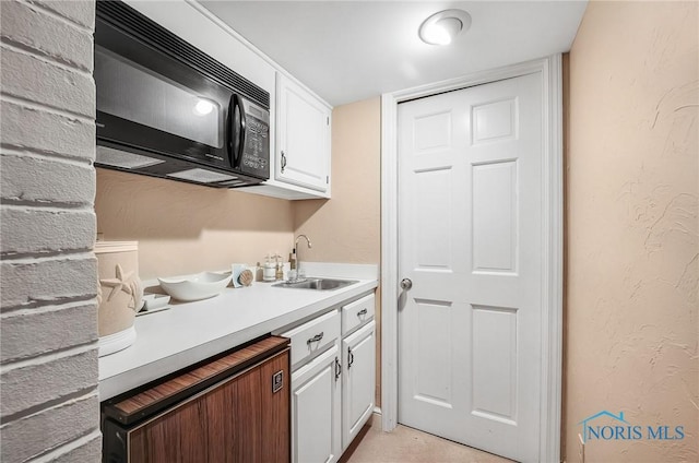25840 W River Rd, Perrysburg, OH 43551 - kitchen featuring a sink, black microwave, white cabinetry, light countertops, and a textured wall
