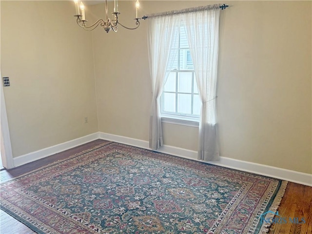 932 N Grove St, Bowling Green, OH 43402 - spare room with a chandelier, baseboards, and wood finished floors