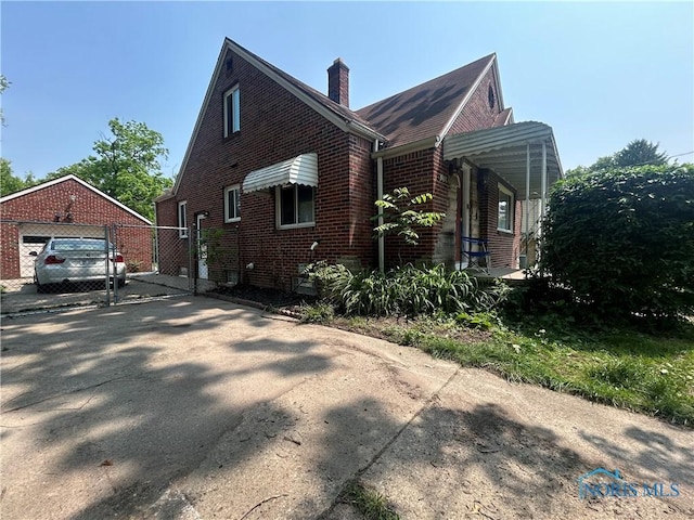 3030 Colby Dr, Toledo, OH 43614 - view of side of property featuring brick siding, a chimney, concrete driveway, a detached garage, and a gate