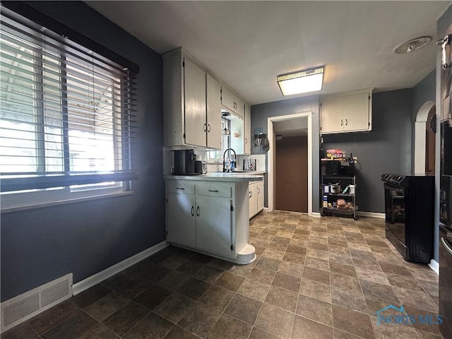 3030 Colby Dr, Toledo, OH 43614 - kitchen with a wood stove, baseboards, light countertops, white cabinets, and dark stone finish floors