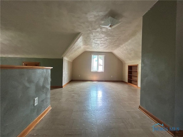 3030 Colby Dr, Toledo, OH 43614 - additional living space with vaulted ceiling, baseboards, a textured ceiling, and built in shelves