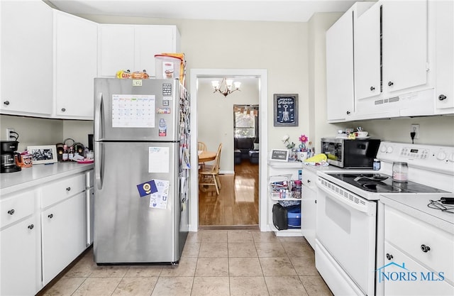 224 Elm St, Rossford, OH 43460 - kitchen with appliances with stainless steel finishes, under cabinet range hood, a chandelier, light countertops, and white cabinetry