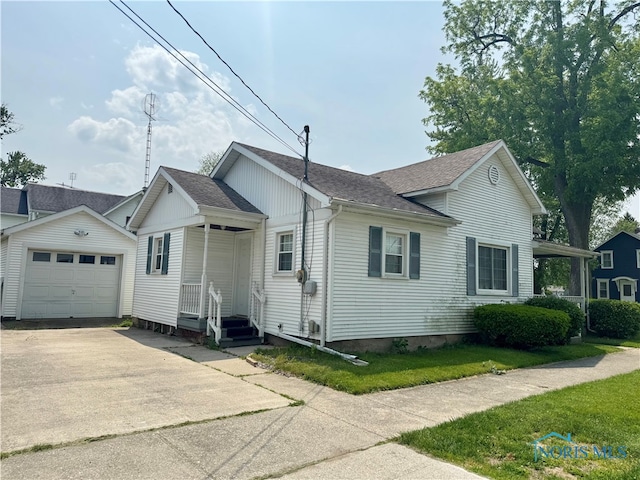 1001 Wilhelm St, Defiance, OH 43512 - view of home's exterior featuring a shingled roof, driveway, a detached garage, an outdoor structure, and a lawn