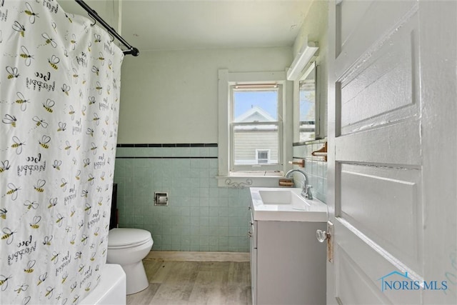 715 Nicholas St, Toledo, OH 43609 - bathroom featuring tile walls, vanity, toilet, wood finished floors, and a wainscoted wall