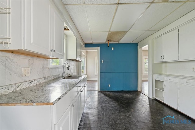 715 Nicholas St, Toledo, OH 43609 - kitchen featuring a sink, a drop ceiling, white cabinetry, light countertops, and decorative backsplash