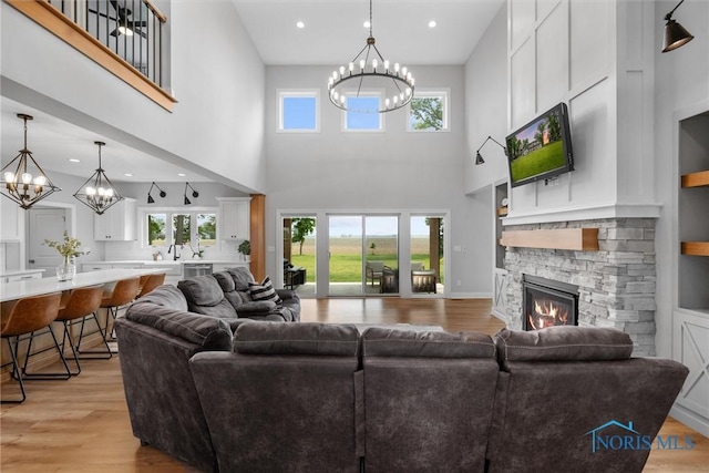 2914 Wingston Rd, North Baltimore, OH 45872 - living area featuring a chandelier, light wood-style flooring, a towering ceiling, a fireplace, and healthy amount of natural light