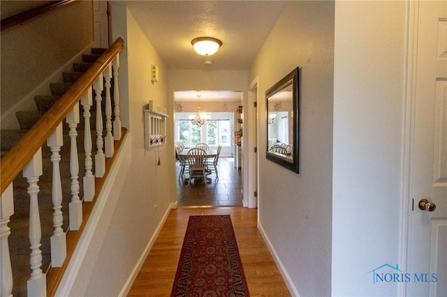 7663 Cortland Ct, Holland, OH 43528 - hallway with stairs, a chandelier, light wood-type flooring, and baseboards