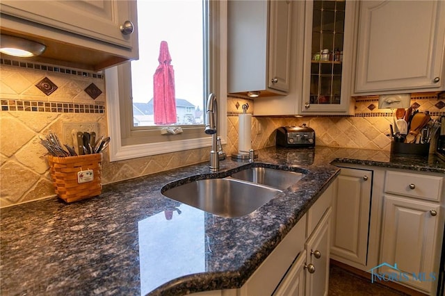 7663 Cortland Ct, Holland, OH 43528 - kitchen with a sink, decorative backsplash, glass insert cabinets, and dark stone countertops