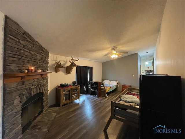 7774 Scott Rd, Edgerton, OH 43517 - living area featuring lofted ceiling, wood finished floors, ceiling fan, a stone fireplace, and a textured ceiling