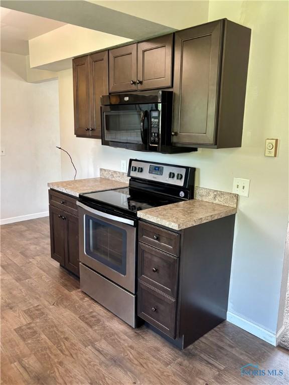 1105 S Lallendorf Rd, Oregon, OH 43616 - kitchen with stainless steel electric stove, black microwave, dark wood-style flooring, dark brown cabinets, and light countertops