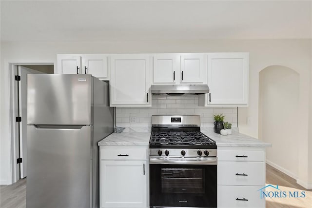 1006 Brookley Blvd, Toledo, OH 43607 - kitchen featuring appliances with stainless steel finishes, under cabinet range hood, light wood-style floors, white cabinets, and light stone countertops