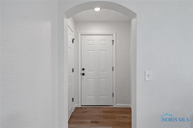 1006 Brookley Blvd, Toledo, OH 43607 - doorway to outside featuring wood finished floors, arched walkways, a textured wall, and baseboards