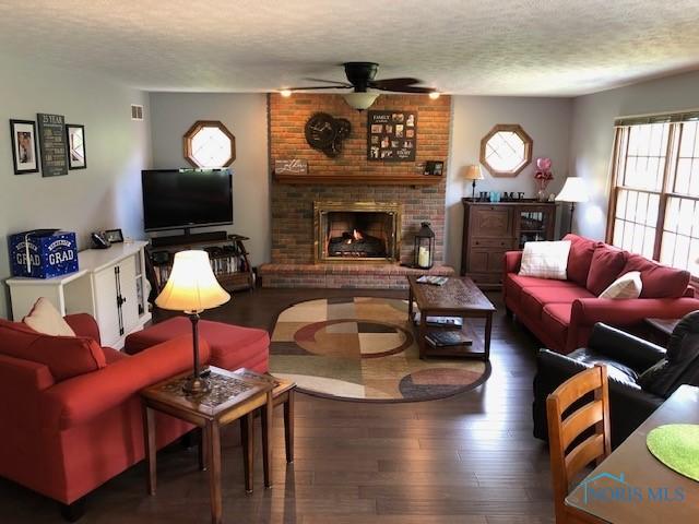 415 W Jamestown Ave, Tiffin, OH 44883 - living area featuring ceiling fan, a textured ceiling, hardwood / wood-style floors, and a brick fireplace