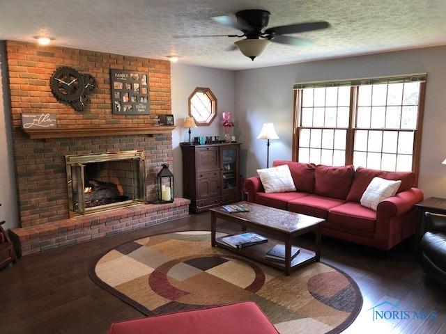 415 W Jamestown Ave, Tiffin, OH 44883 - living area featuring ceiling fan, wood finished floors, a brick fireplace, and a textured ceiling