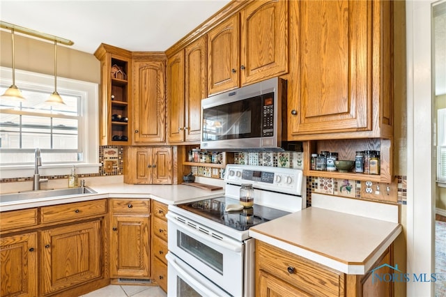 713 N Vine St, Fostoria, OH 44830 - kitchen with stainless steel microwave, range with two ovens, a sink, open shelves, and brown cabinetry