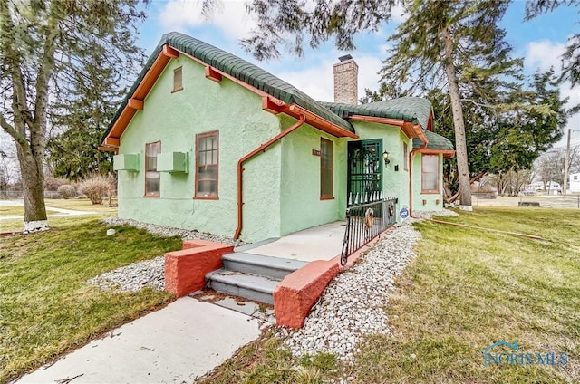 7149 Wales Rd, Northwood, OH 43619 - view of front of home with stucco siding, a chimney, and a front lawn