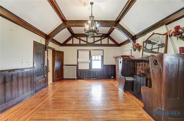 7149 Wales Rd, Northwood, OH 43619 - unfurnished living room with light wood-type flooring, wainscoting, radiator heating unit, arched walkways, and a chandelier