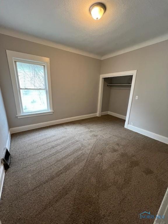 928 Islington St, Toledo, OH 43610 - unfurnished bedroom with dark carpet, baseboards, a textured ceiling, and a closet