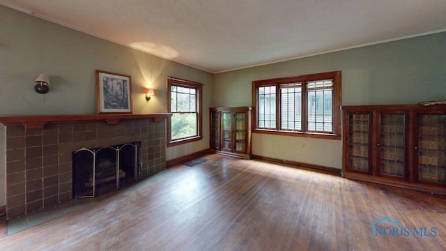 2720 Scottwood Ave, Toledo, OH 43610 - unfurnished living room with wood finished floors, a tile fireplace, baseboards, and crown molding