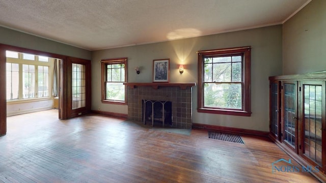 2720 Scottwood Ave, Toledo, OH 43610 - unfurnished living room featuring baseboards, wood finished floors, a tile fireplace, plenty of natural light, and ornamental molding