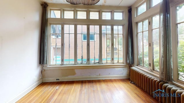 2720 Scottwood Ave, Toledo, OH 43610 - unfurnished sunroom with radiator, baseboards, and hardwood / wood-style flooring