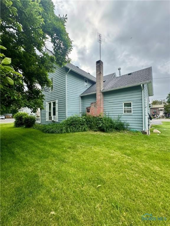 308 S Main St, Hicksville, OH 43526 - rear view of house featuring a chimney, a lawn, and a shingled roof