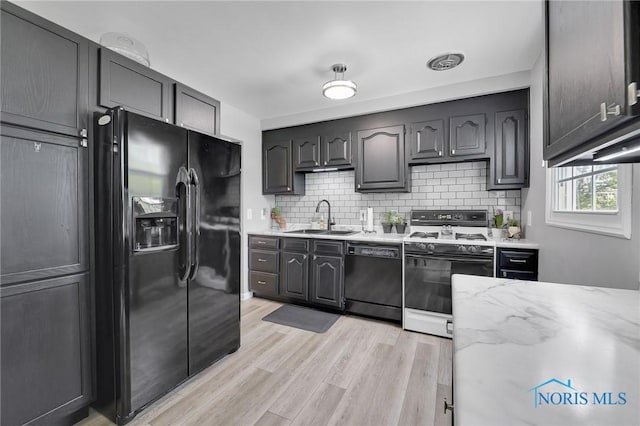 2444 Jamestown Dr, Northwood, OH 43619 - kitchen with black appliances, a sink, backsplash, light wood-style flooring, and light stone counters