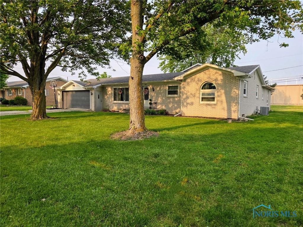 808 W St, Archbold, OH 43502 - ranch-style house with brick siding, a garage, a front lawn, and central air condition unit