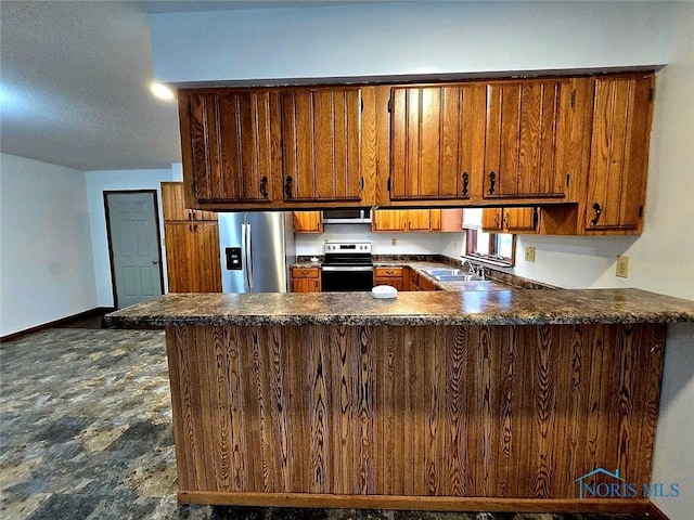 711 Circle Dr, Fostoria, OH 44830 - kitchen with stainless steel appliances, a peninsula, brown cabinetry, and dark countertops