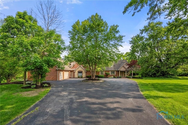 16890 W River Rd, Bowling Green, OH 43402 - view of front of house featuring asphalt driveway, a garage, a front yard, and brick siding