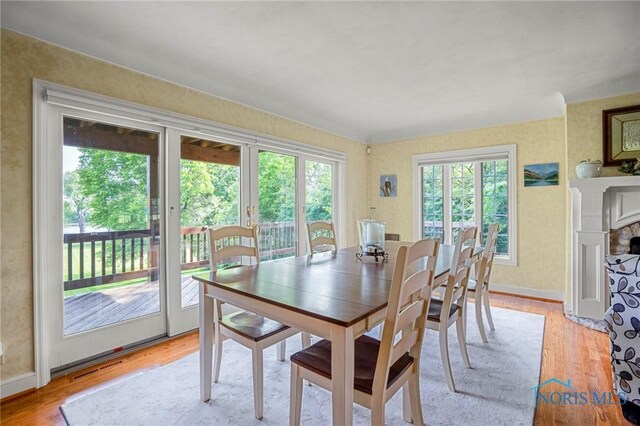 16890 W River Rd, Bowling Green, OH 43402 - dining room featuring healthy amount of natural light, light wood finished floors, a stone fireplace, and wallpapered walls