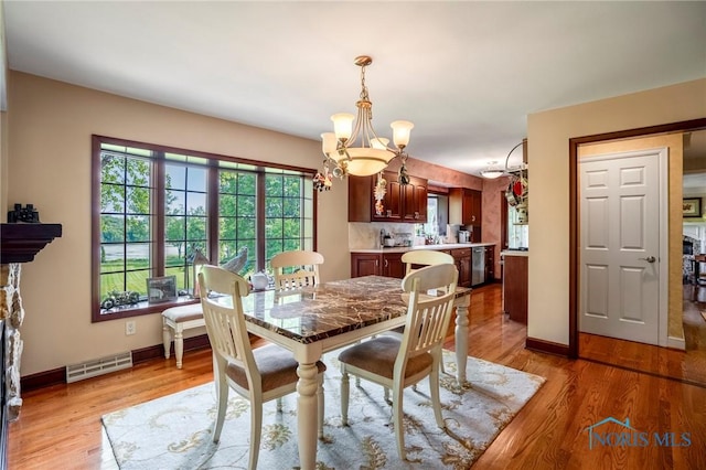 16890 W River Rd, Bowling Green, OH 43402 - dining area with a chandelier, baseboards, and light wood-style floors