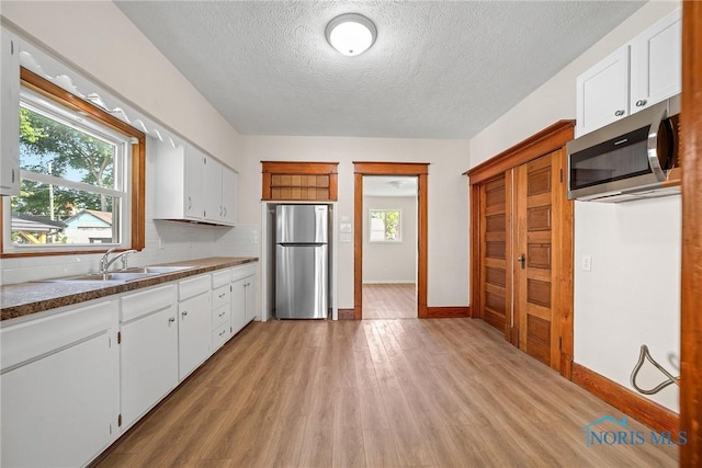 230 W S St, Fostoria, OH 44830 - kitchen featuring stainless steel appliances, healthy amount of natural light, a textured ceiling, light wood-style flooring, and white cabinetry