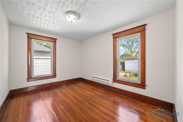 230 W S St, Fostoria, OH 44830 - unfurnished room featuring baseboard heating and dark wood-type flooring