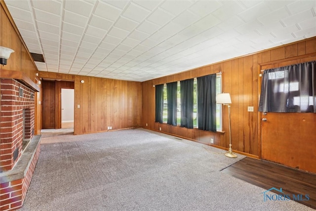 308 Edith Ave, Findlay, OH 45840 - unfurnished living room featuring a brick fireplace, wood walls, and carpet flooring