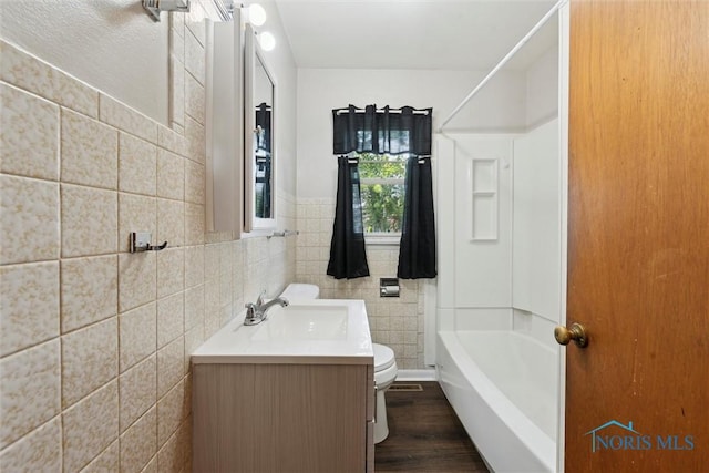 308 Edith Ave, Findlay, OH 45840 - bathroom featuring toilet, vanity, tile walls, wood finished floors, and tub / shower combination