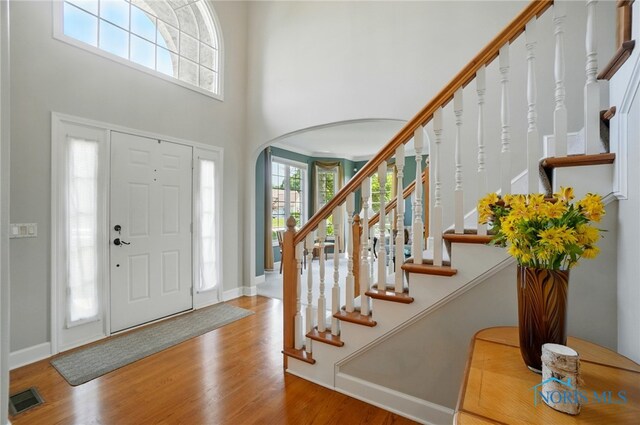 7433 Valhalla Dr, Maumee, OH 43537 - foyer with arched walkways, wood finished floors, stairway, a high ceiling, and baseboards