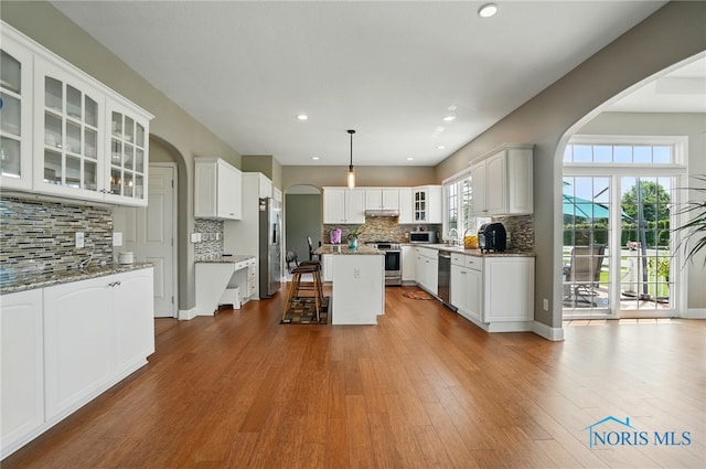 7433 Valhalla Dr, Maumee, OH 43537 - kitchen with appliances with stainless steel finishes, arched walkways, a breakfast bar area, tasteful backsplash, and white cabinetry