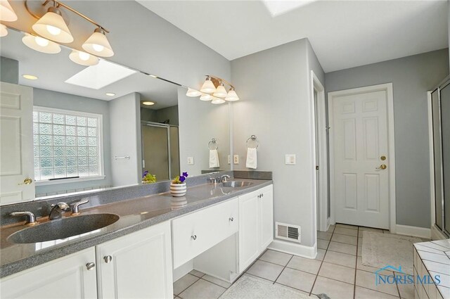 7433 Valhalla Dr, Maumee, OH 43537 - full bath with a shower stall, double vanity, a skylight, and tile patterned floors