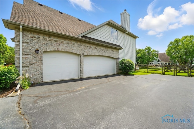 7433 Valhalla Dr, Maumee, OH 43537 - view of home's exterior featuring asphalt driveway, a chimney, a garage, and roof with shingles