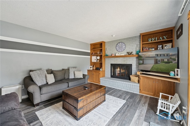 2546 Redfox Dr, Toledo, OH 43611 - living room with a textured ceiling, dark wood-style floors, and a brick fireplace
