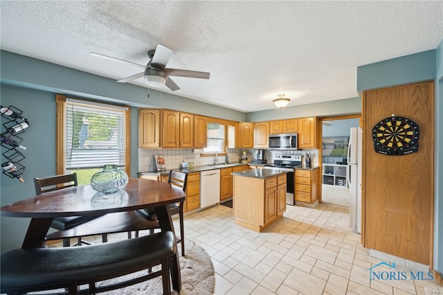 2546 Redfox Dr, Toledo, OH 43611 - kitchen with appliances with stainless steel finishes, healthy amount of natural light, a kitchen island, decorative backsplash, and a textured ceiling