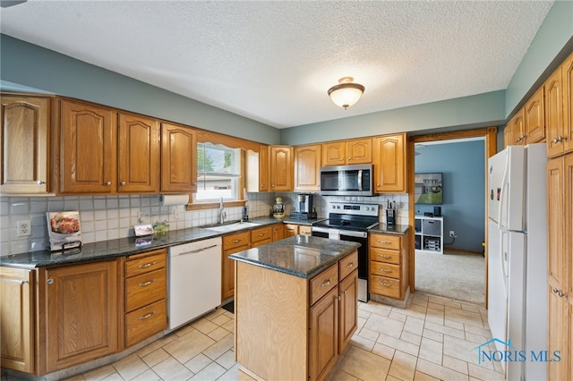 2546 Redfox Dr, Toledo, OH 43611 - kitchen featuring appliances with stainless steel finishes, a sink, decorative backsplash, a kitchen island, and dark stone counters