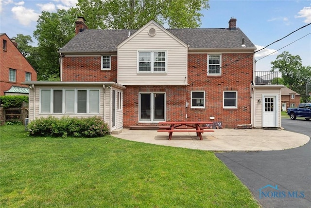 2829 Pembroke Rd, Ottawa Hills, OH 43606 - back of house with a chimney, a lawn, brick siding, and a patio