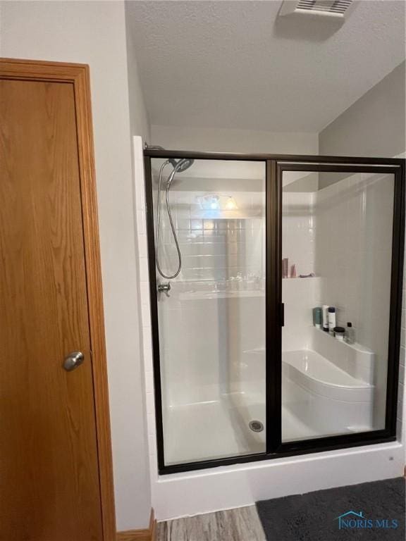 606 Polaris Dr, Upper Sandusky, OH 43351 - bathroom featuring a shower stall, a textured ceiling, and wood finished floors
