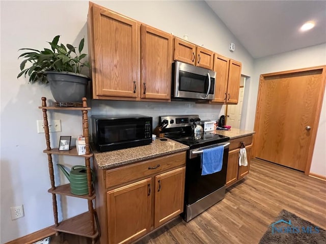 606 Polaris Dr, Upper Sandusky, OH 43351 - kitchen featuring stainless steel appliances, lofted ceiling, wood finished floors, light stone counters, and brown cabinets